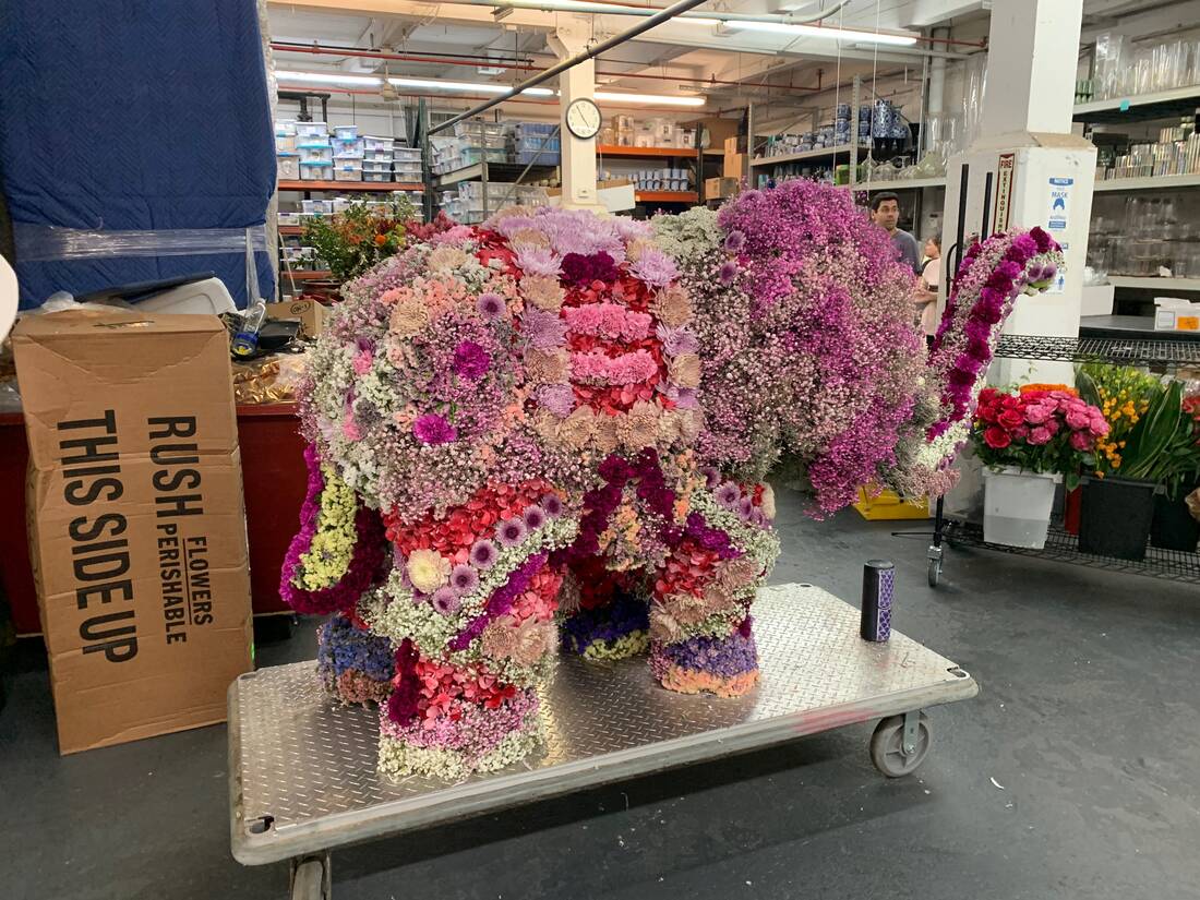 Life-size elephant sculpture covered in fresh pink and magenta flowers