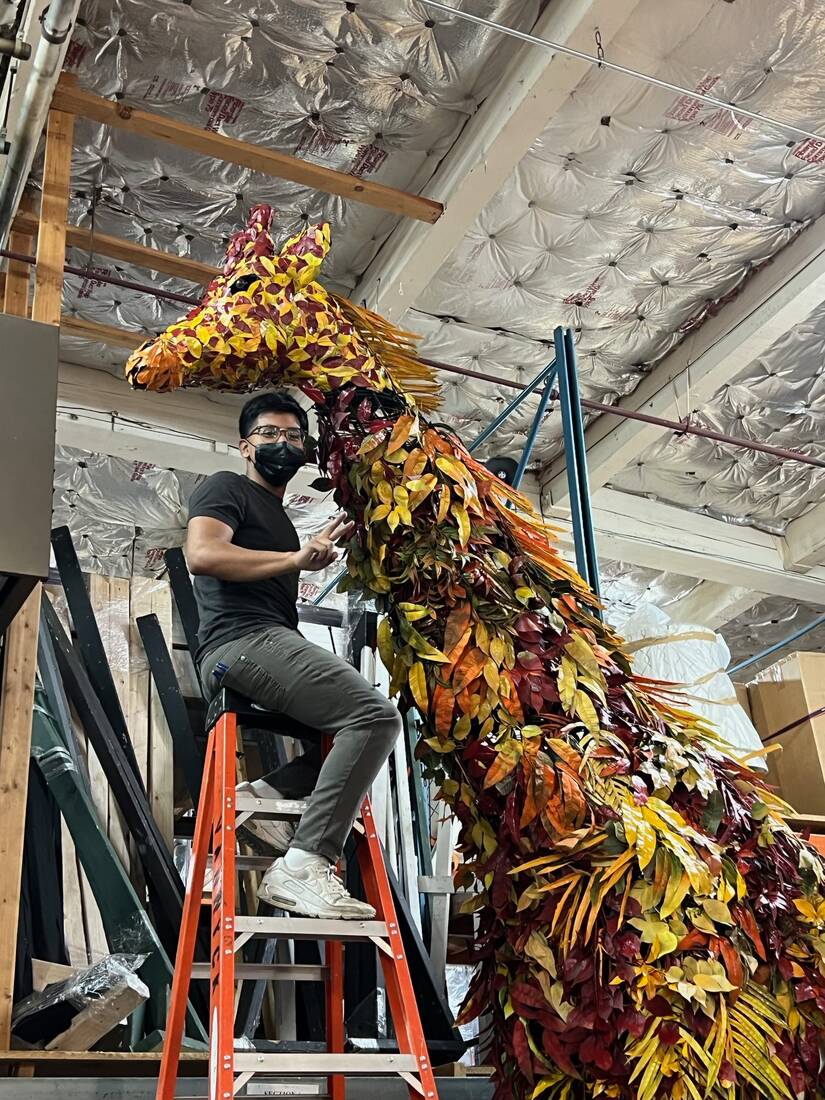 Two-story giraffe sculpture built from autumn foliage