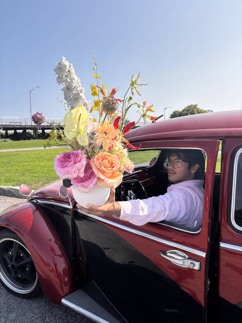 An arrangement of garden roses and gloriosa passed from the window of a vintage car